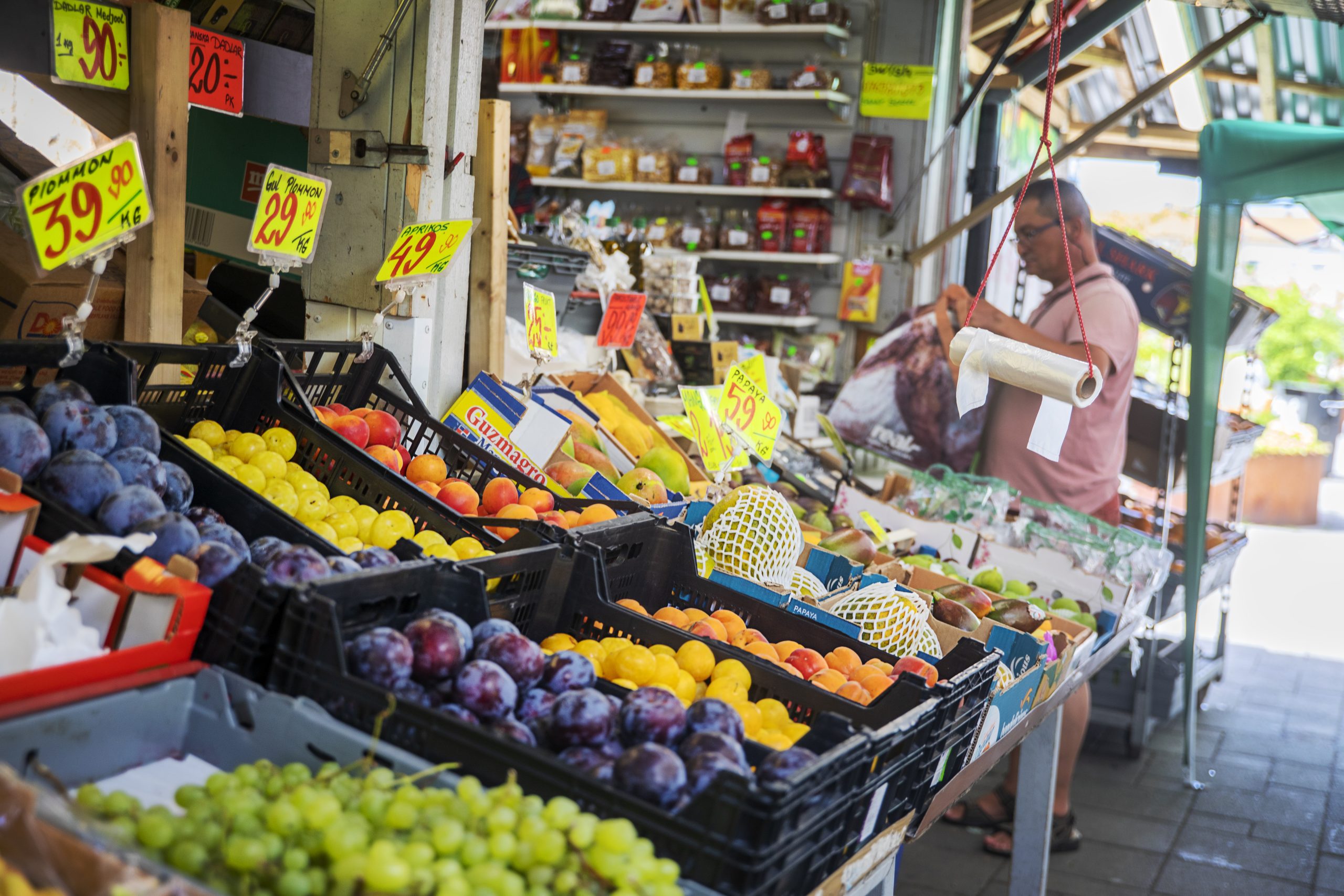 Frukthandel med plommon, vindruvor, mango och andra exotiska frukter med skyltar som visar priset.