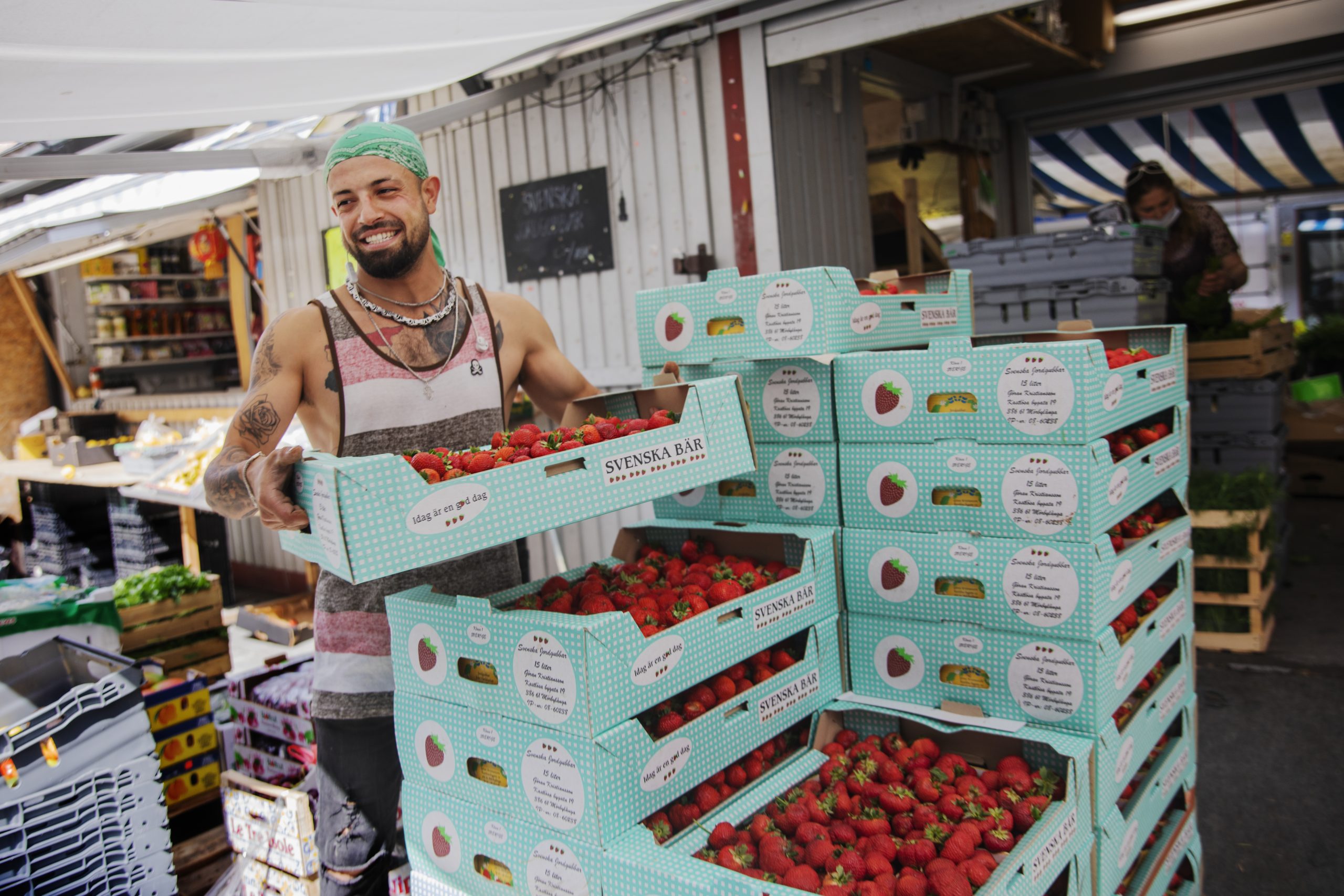 En frukthandlare staplar lådor med jordgubbar i.
