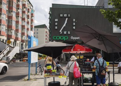 Bärförsäljning under parasoll framför en matvarubutik.